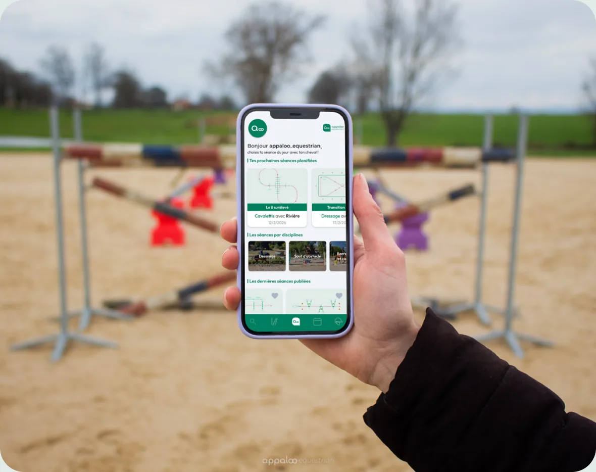 L'application Appaloo Equestrian sur un téléphone, devant une carrière